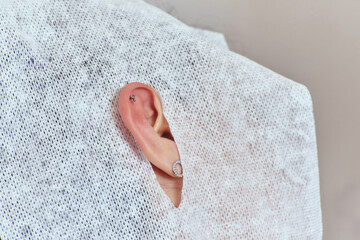 piercings on an ear. Conch and helix piercings close up. Professional holding the jewel. - obrazy, fototapety, plakaty