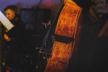 Concert view of violoncello player with vocalist and musical orchestra band, during jazz concert, performing music, violoncellist cello jazz player on stage, old retro vintage contrabass - obrazy, fototapety, plakaty