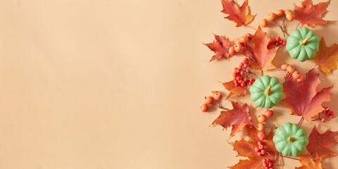 Naklejka na ściany i meble Flat lay frame with colorful autumn leaves and pumpkins on an orange background