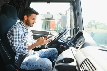 Young handsome indian man using smart phone in his truck.