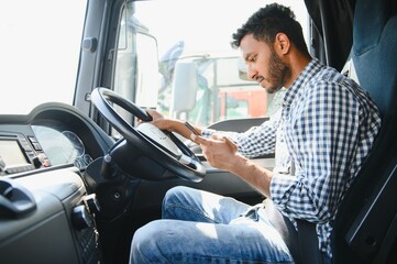 Young handsome indian man using smart phone in his truck.