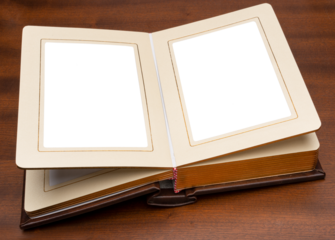 Opened photo album in brown cover with gold trim of pages, top view. Laying on a wooden table top.