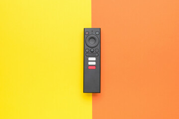 Modern TV remote control on a yellow-orange background. TV management concept. - obrazy, fototapety, plakaty
