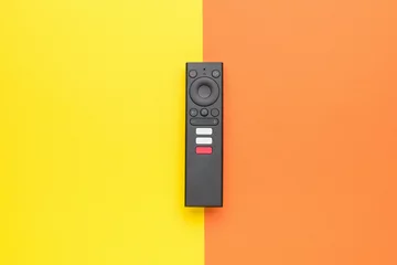 Fotobehang Modern TV remote control on a yellow-orange background. TV management concept. © kvladimirv
