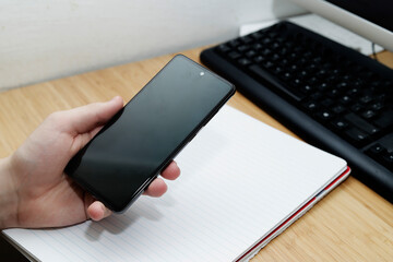 boy's hand with cell phone on desk