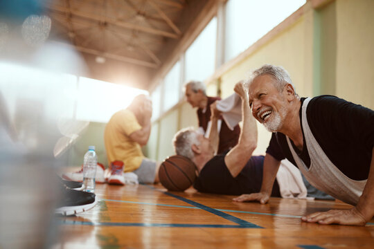 Diverse group of male seniors doing push ups and working out after playing basketball in an indoor gym - Powered by Adobe