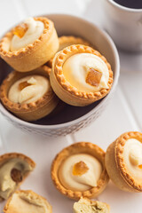 Sweet tarlets. Tasty mini tarts. Mini pie with cream in bowl on kitchen table.
