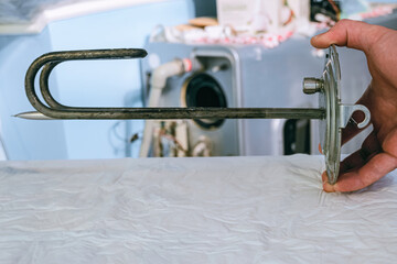Serviceman holds heating element of an electric water heater in his hand. Service and repair.