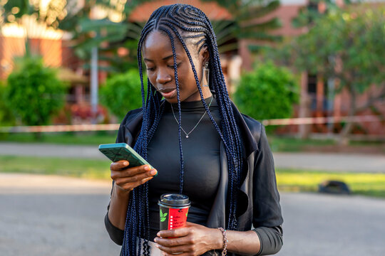 young African woman with braids looking at her cell phone