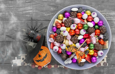 decorated holiday table Halloween Jack o Lantern candy bowl with sweets and halloween cookies Trick or Treat dark background