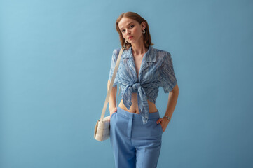 Fashionable young woman wearing  knotted chiffon blouse, trousers, carrying trendy white leather...