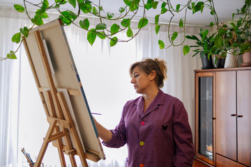 Adult woman painting canvas at home