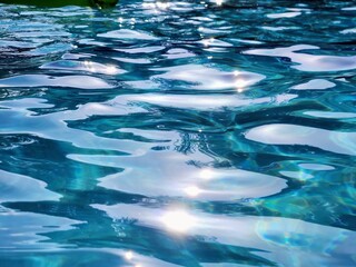Blue water surface in swimming pool with sun reflections. Abstract background.