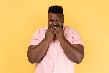 Portrait of panicking man in pink shirt biting nails, being nervous terrified, feeling frightened...