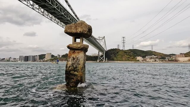 View of Stone lantern basket of Kazuki Kari Shrine and Kanmon Strait under gray sky in Japan