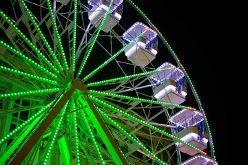 a large ferris wheel at night with green lights and bright blue lights
