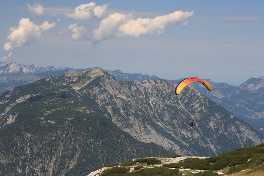 Alps. Dachstein Mountains. Austria. Paraplaner gliding in blue sky with view on Alpine mountains on paraplane