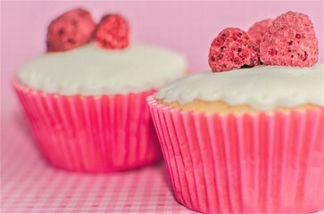 Two pink strawberry cupcakes with pink background