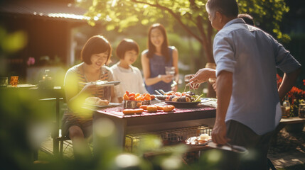 asian family and friends having fun at picnic with barbecue in the garden

