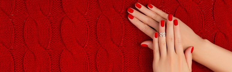 Womans hands with matt manicure on red knitted coverlet. Winter manicure, pedicure design trends
