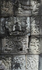 Fototapeta na wymiar Vertical of stone carvings of Khmer warriors in chariots and war horses in Angkor Wat temple