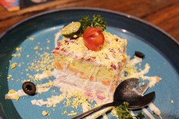 Plated dish of a layered sushi tower on a blue plate