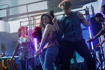 Young passionate dancers couple making energetic moves on dancefloor in nightclub. Active man and woman dancing together while partying and clubbing at discotheque social gathering