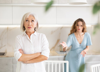 Quarrel of an elderly mother and adult daughter at home. Adult daughter is unhappy with elderly mother