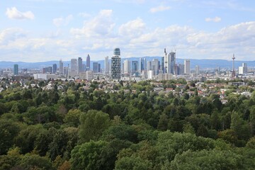 Fototapeta na wymiar Panoramic view of the Frankfurt skyline with green forest in the foreground on a sunny day.