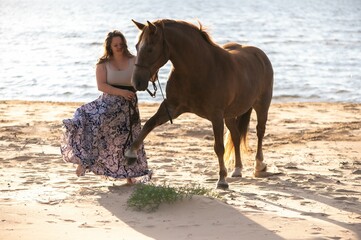Female rider galloping along a beach on a brown horse.