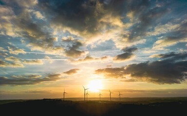 Idyllic landscape featuring a field of windmills silhouetted against a vivid sunset sky