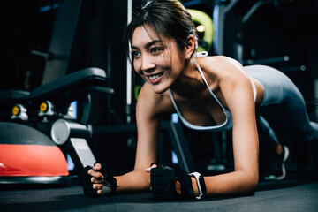 Fototapeta na wymiar Fit young woman maintaining a plank position on a stability ball to improve core strength and balance during her indoor gym workout, exercise in dark gym background