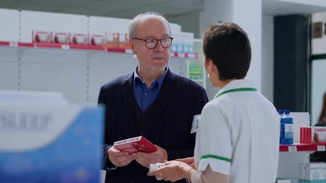 Qualified pharmacy physician helping old man with medical counsel. Senescent client in chemist store wishing to purchase heartbeat regulating antibiotics, asking expert for guidance