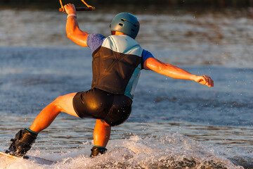 An athlete performs a trick on the water. Park at sunset. Wakeboard rider