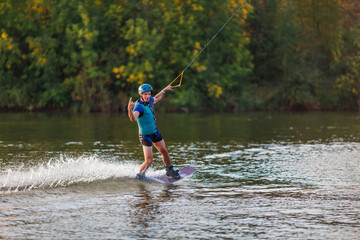 An athlete performs a trick on the water. Park at sunset. Wakeboard rider