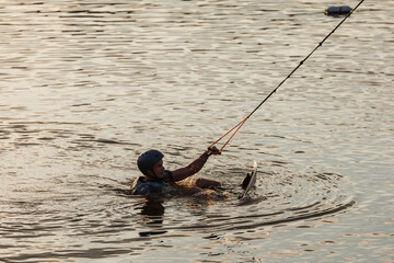 An athlete performs a trick on the water. Park at sunset. Wakeboard rider