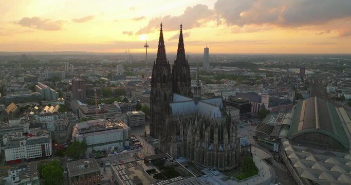 The most popular view of Cologne city center. Above railway bridge over wide river. Silhouette of two towers of Cologne Cathedral against glowing sunset sky. Establishing shot Cologne, Germany