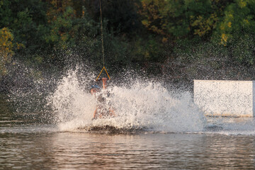 An athlete performs a trick on the water. Park at sunset. Wakeboard rider