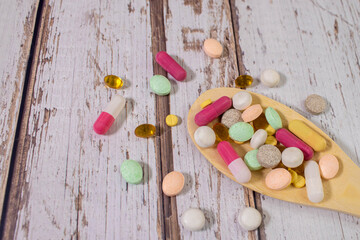 Assorted pharmaceutical medicine pills, tablets and capsules on wooden spoon