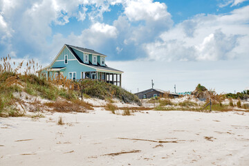Beach houses on the shores of the Atlantic Ocean. White sand, under snow-white clouds.
