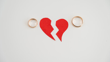 Broken heart and wedding rings on a white background. Divorce concept.