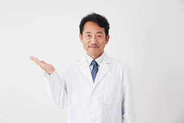 左側を手の平で指す中年の医師　白背景