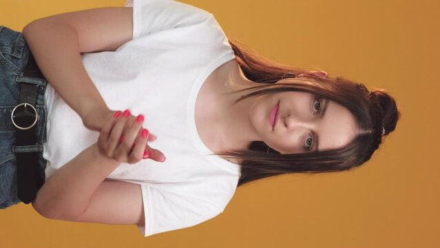 Vertical video. Sarcastic expression. Skeptic emotion. Disappointed doubtful woman clapping hands thumb up gesture sign isolated on orange background.