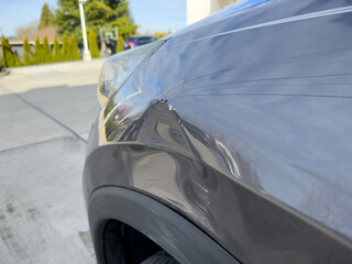 Close up view of a dent on the left side of a gray vehicle