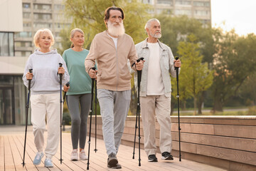 Group of senior people performing Nordic walking outdoors. Low angle view