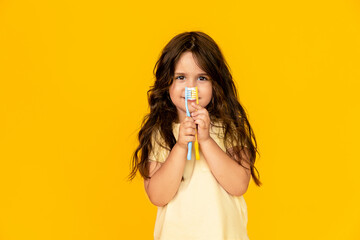 Twice faster. Child girl holds two toothbrushes. Child preschool girl smart kid happy face cares hygiene. Brush teeth concept. Teeth hygiene. Girl cute long hair holds toothbrushes yellow background.