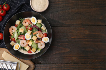Delicious Caesar salad with shrimps and ingredients on wooden table, flat lay. Space for text