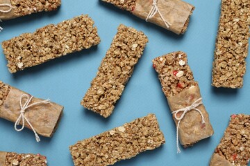 Different tasty granola bars on light blue background, flat lay