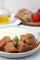 Delicious goulash served with mashed potato on table, closeup