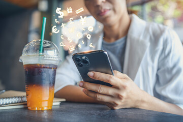 Woman holding smartphone with shopping application icons comming out at cafe. Business women using cellphone online connect network technology, internet of things concept. - obrazy, fototapety, plakaty